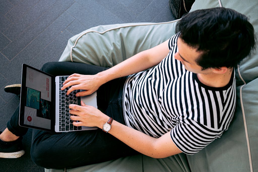 The Home of The Global Association of One Percenters 6 blog image A man in a striped shirt using a laptop on a bean bag, embodying relaxed productivity. transulate image for the global assocaition of one percenters