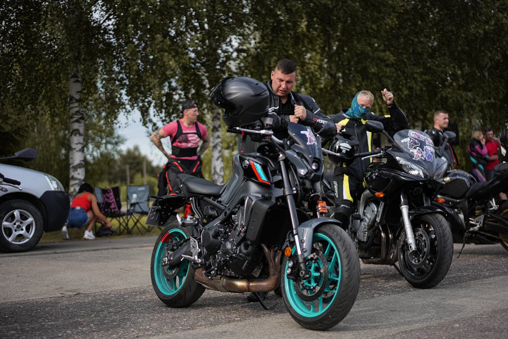 The Home of The Global Association of One Percenters 13 Group of motorcyclists adjusting gear beside bikes at a meetup on a sunny day. for The Global Association of One Percenters for GAOP History and local club membership