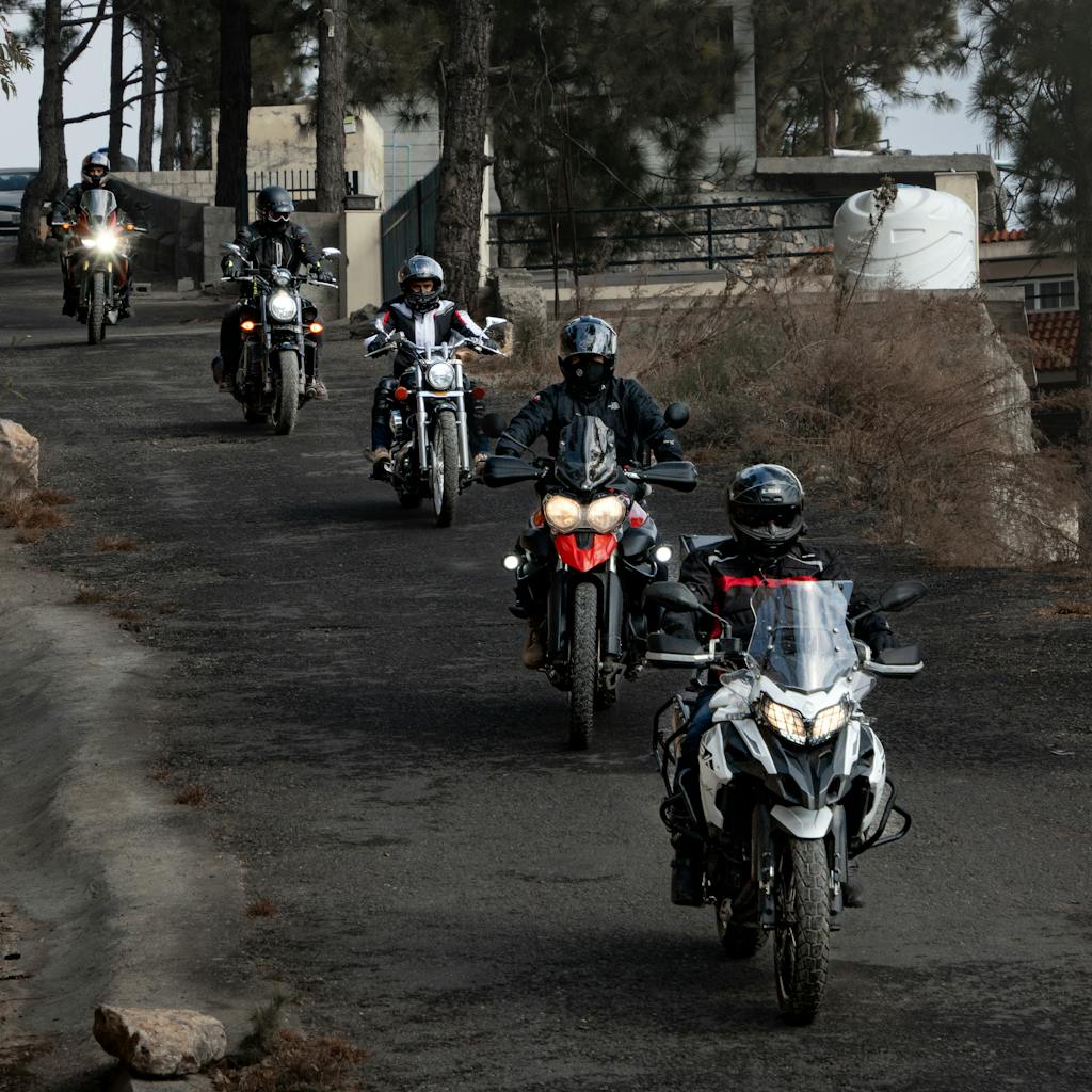 Group of motorcyclists on a scenic ride through a tree-lined rural area. for The Global Association of One Percenters and national club membership page
